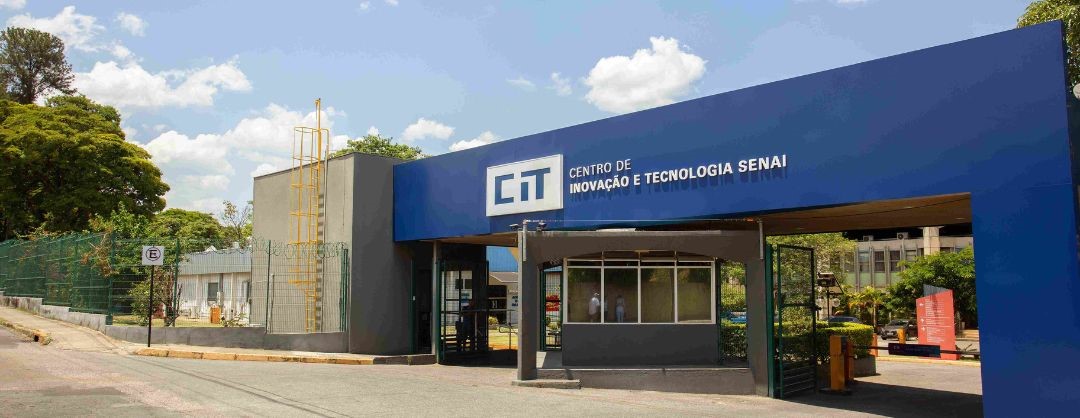 Pórtico azul de entrada do CIT — Centro de Inovação e Tecnologia SENAI, com guarita e área arborizada ao fundo